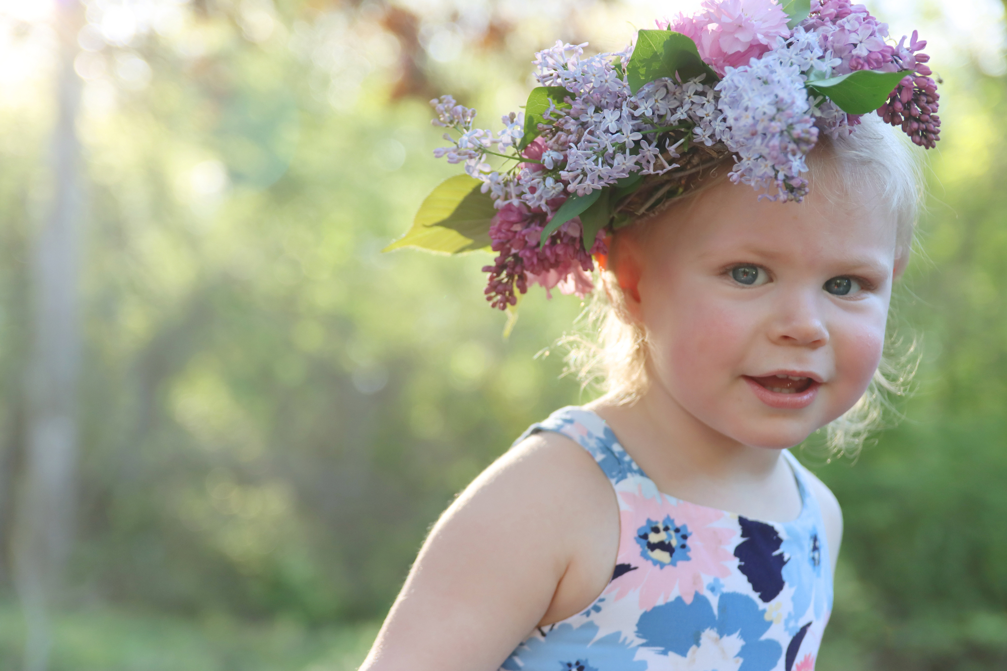 young girl with blonde hair and a lilac flower grown on her head
