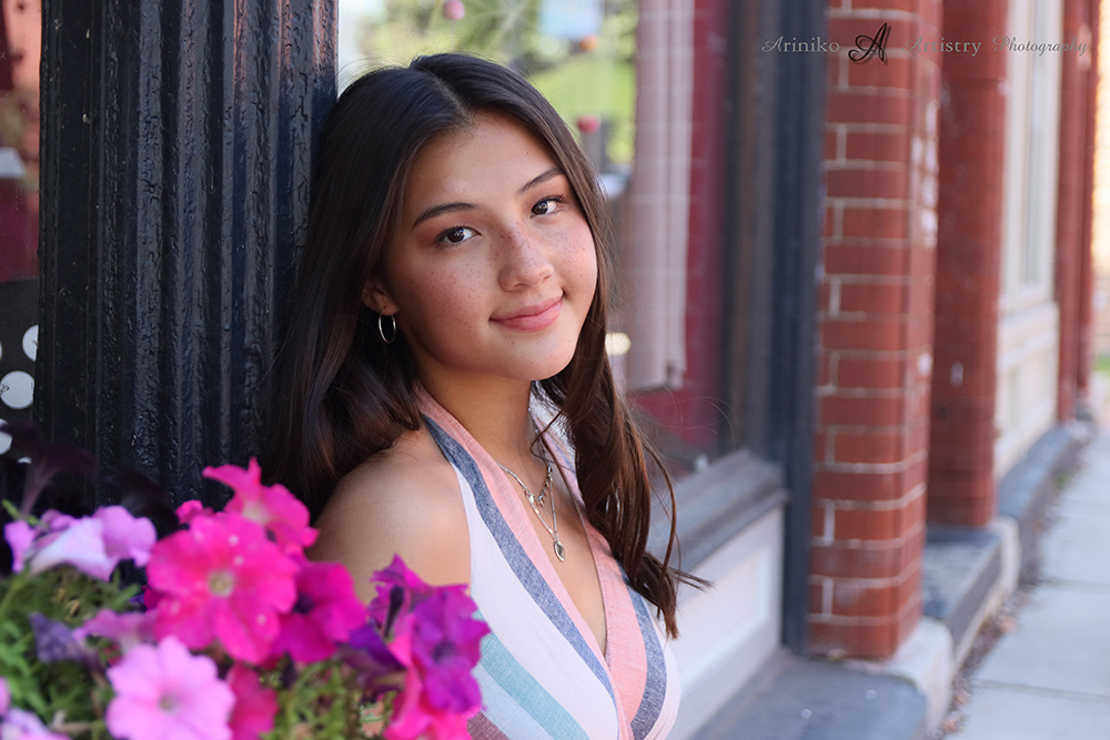 young female High school senior posing in Old Town Lansing, Michigan for her senior portraits