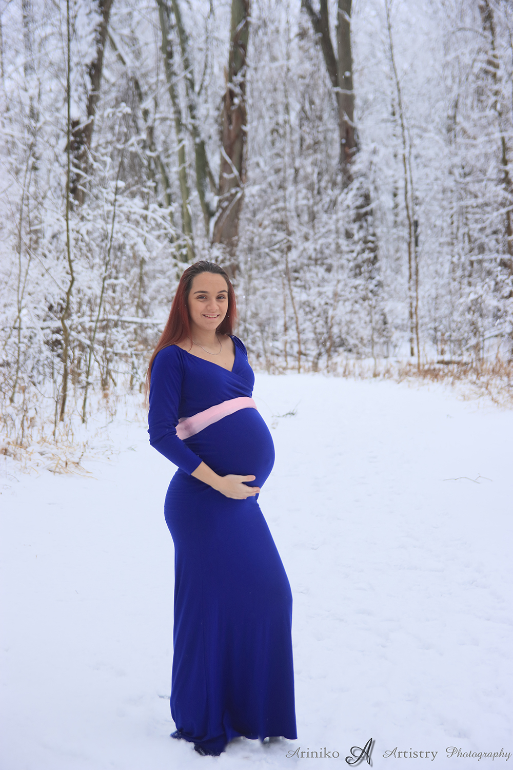 Young pregnant woman posing in a royal blue dress at Harris Nature Center in Okemos, Michigan