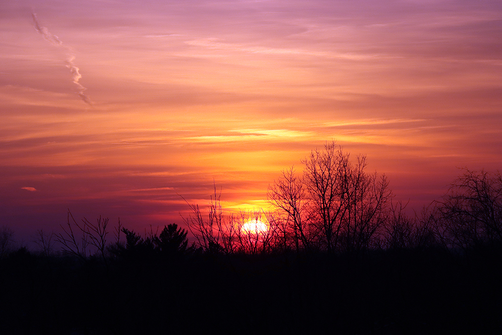 Sunset of orange, maroon, burgundy and purple from the top of Granger Meadow sledding hill in DeWitt, Michigan