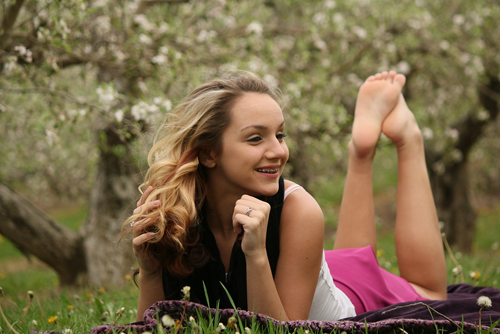 young lady laying on a blanket in Uncle John's Cider Mill's apple orchard