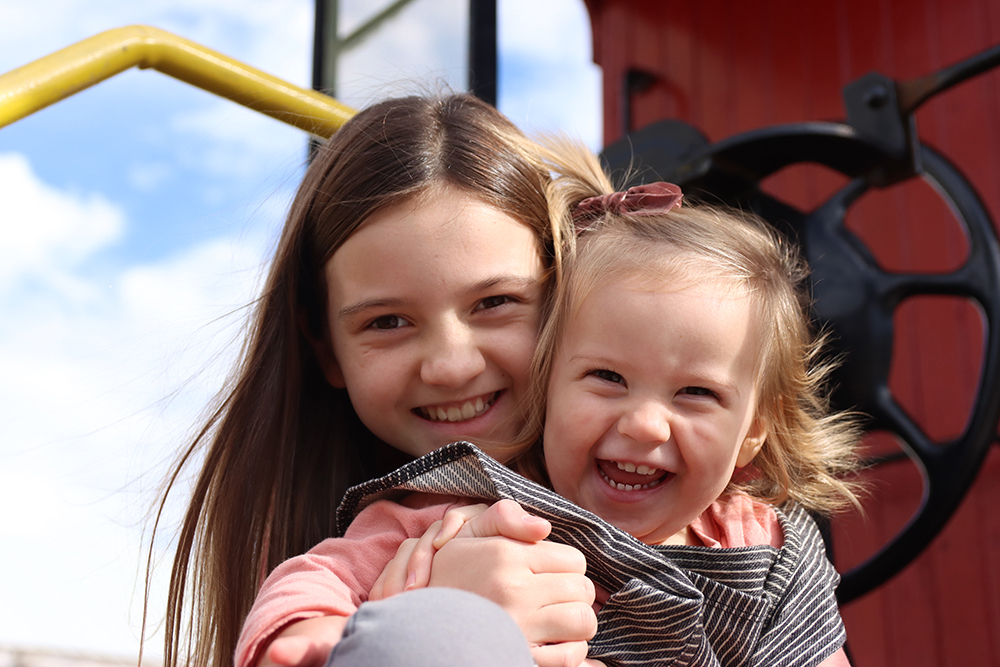 sisters laughing during an Ariniko Artistry photo shoot in St. Johns Michigan