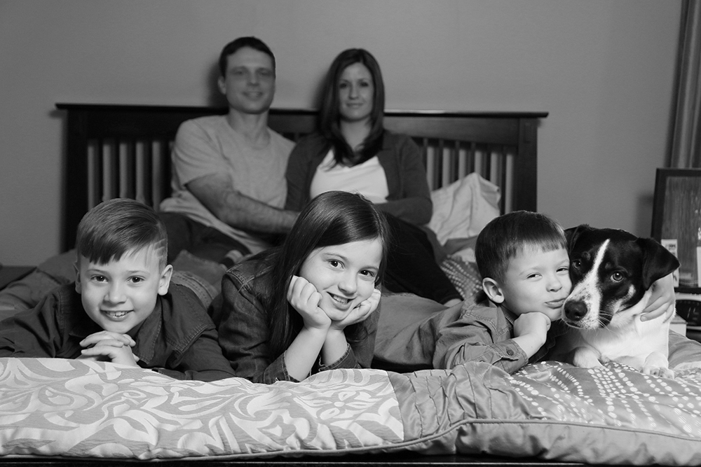 Family maternity session on bed in parent's room