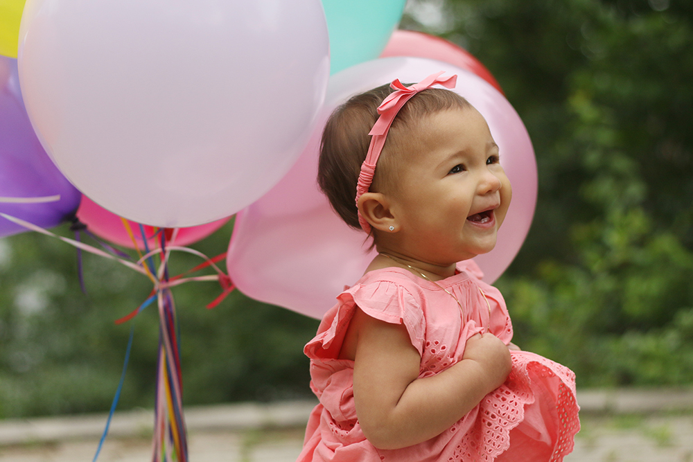 Little girl celebrating her first birthday with balloons