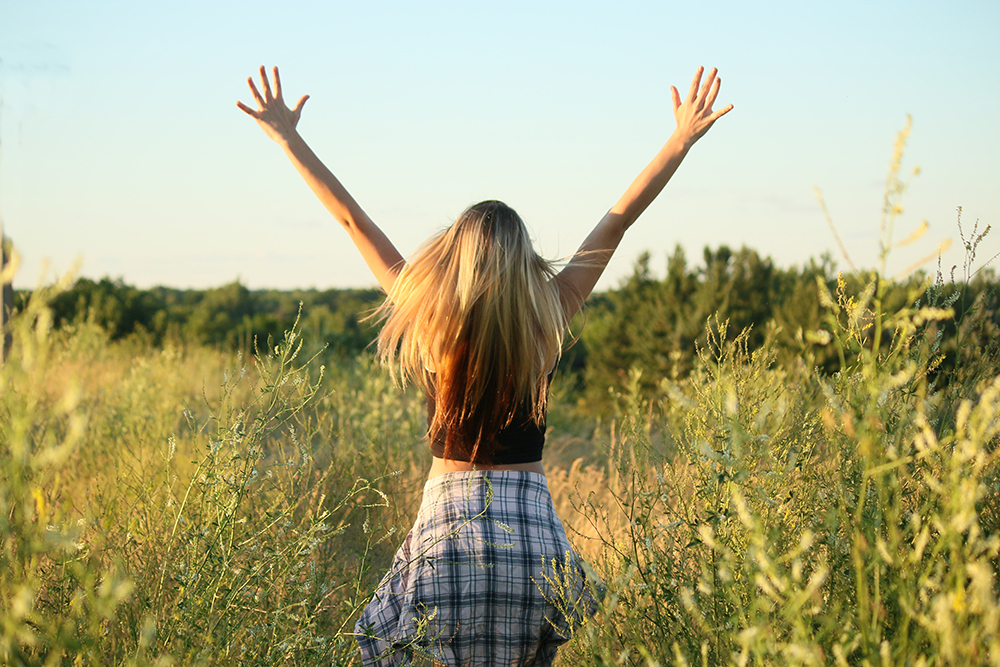 Young woman walking through field for her senior portraits