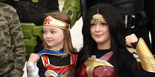 a young girl dressed like Wonder Woman hugging a woman dressed like Wonder Woman