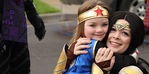 a young girl dressed like Wonder Woman hugging a woman dressed like Wonder Woman