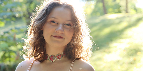 Young women posing for her senior portraits back lit with a ray of sunshine