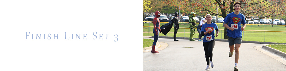 two young people run towards the finish like with Superman t-shirts on