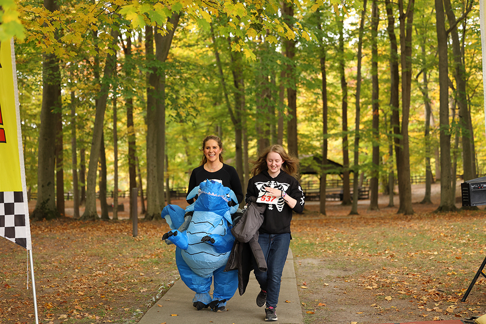 Racer riding a blow-up blue dragon for the Dragon in the Woods 5k
