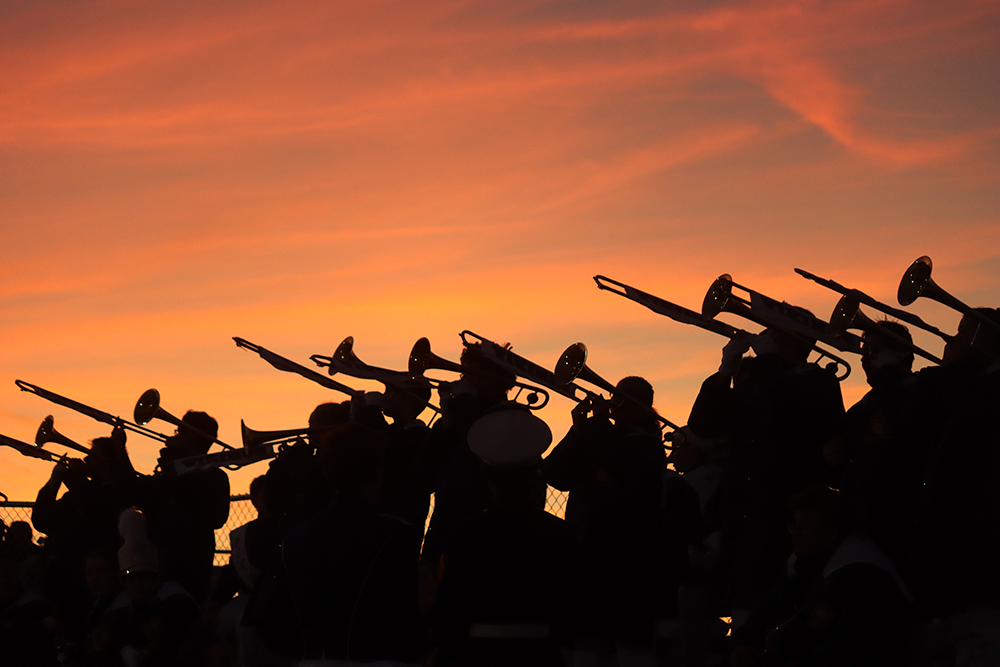 The Haslett High School trombone section against a bright red sunset 