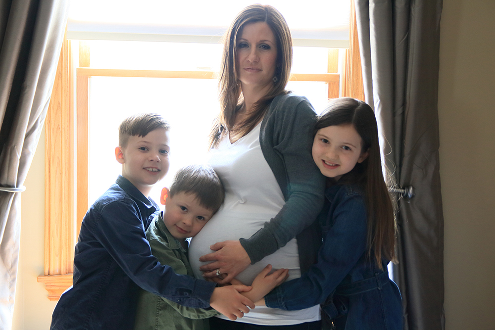 Pregnant mom with her three children posing in a windowsill