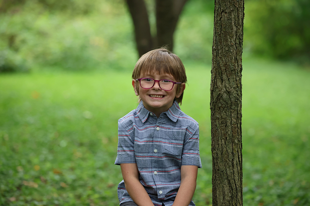 Little boy wearing glasses in sitting and posing for the photo